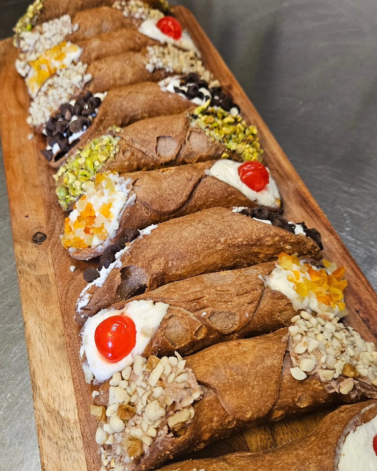 A board of freshly filled Sicilian cannoli